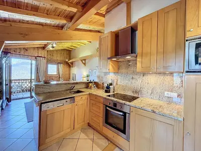 a large kitchen with wooden cabinets and appliances at Appartement 3 pièces tout équipé avec balcon et box fermé, à 1,2 km du centre de Combloux - FR-1-560-141 in Combloux
