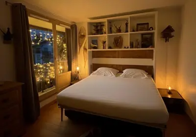 a bedroom with a bed and a window with lights at CHAMONIX Centre - Studio de charme avec parking, Vue sur le Mont-Blc in Chamonix-Mont-Blanc