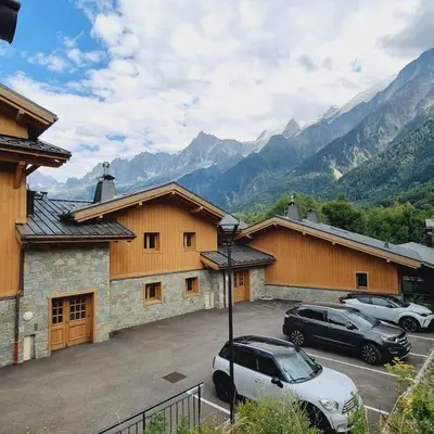 two cars parked in a parking lot in front of a building at MGM Charles Delys - 3 Rooms - Les Houches in Les Houches