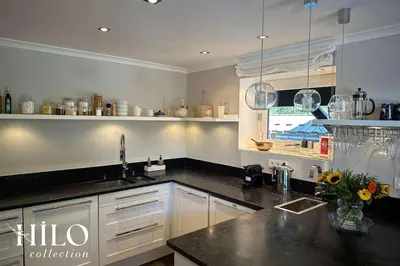 a kitchen with white cabinets and a black counter top at Chalet La Moraine Chamonix Mont Blanc by HILO Collection - 8 people - Jacuzzi and PS5 in Chamonix-Mont-Blanc