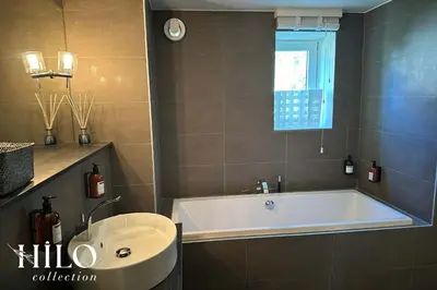 a bathroom with a bath tub and a sink at Chalet La Moraine Chamonix Mont Blanc by HILO Collection - 8 people - Jacuzzi and PS5 in Chamonix-Mont-Blanc