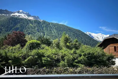 a view of a mountain with trees and a building at Chalet La Moraine Chamonix Mont Blanc by HILO Collection - 8 people - Jacuzzi and PS5 in Chamonix-Mont-Blanc