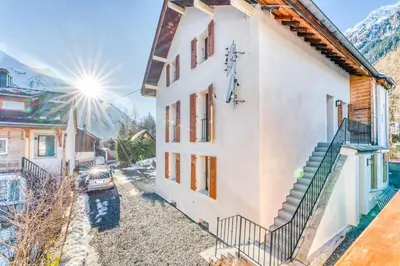 a white house with a car parked next to it at Chalet L'Argoat - Warm and cosy 6 bedroom chalet in Chamonix-Mont-Blanc