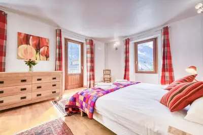 a bedroom with a large bed and two windows at Chalet L'Argoat - Warm and cosy 6 bedroom chalet in Chamonix-Mont-Blanc