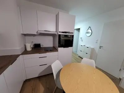 a kitchen with a wooden table and white cabinets at Appartement proche télécabine in Saint-Gervais-les-Bains