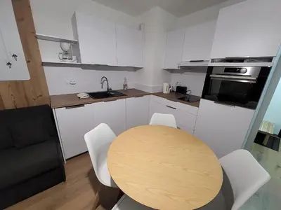 a kitchen with a wooden table and white cabinets at Appartement proche télécabine in Saint-Gervais-les-Bains