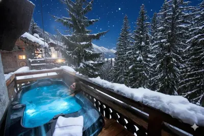 a log cabin with a bench in front of it at night at Hôtel Les Chalets de Philippe avec Jacuzzis Privatifs in Chamonix-Mont-Blanc