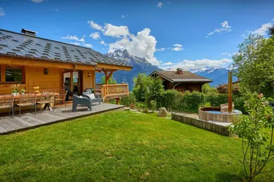a wooden house with a patio and a lawn at Chalet Anselme - OVO Network in Cordon