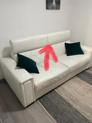 a white couch with two pillows and a red ribbon at studio station des carroz d'arraches in Arâches-la-Frasse
