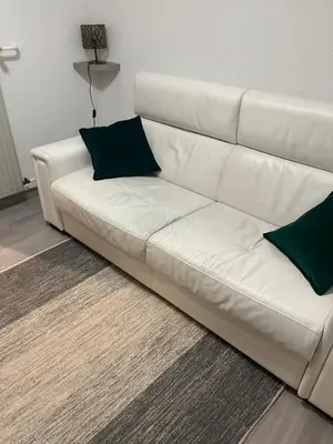 a white couch in a living room with green pillows at studio station des carroz d'arraches in Arâches-la-Frasse