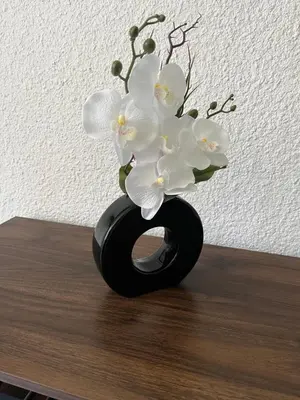 a black vase with white flowers in it on a table at studio station des carroz d'arraches in Arâches-la-Frasse