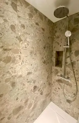 a shower in a bathroom with a stone wall at Appartement 4 personnes centre village in Samoëns