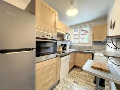 a kitchen with wooden cabinets and a table in it at Chamonix : Appartement 63 m², 6 pers, Confort & Wifi - FR-1-507-78 in Chamonix-Mont-Blanc