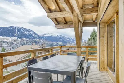 a table and chairs on a balcony with mountains at Chalet de Denis luxe alpin et emplacement ideal à Megeve in Megève
