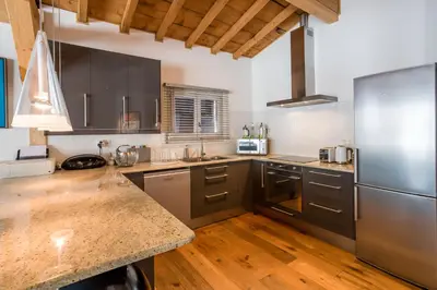 a large kitchen with stainless steel appliances and wooden floors at Le Bartavel Apartment - Chamonix All Year in Chamonix-Mont-Blanc