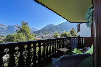 a balcony with a table and chairs and mountains at Charming T2 in Saint-Gervais-les-Bains in Saint-Gervais-les-Bains