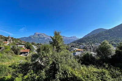 a town on a hill with mountains in the background at Charming T2 in Saint-Gervais-les-Bains in Saint-Gervais-les-Bains