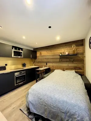 a bedroom with a large bed and a kitchen at Centre village station ski in Saint-Gervais-les-Bains