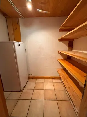 a small kitchen with a refrigerator and wooden shelves at Appartement Chamonix in Chamonix-Mont-Blanc