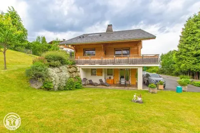 a wooden house with a deck and a yard at Chalet des Morets in Saint-Gervais-les-Bains