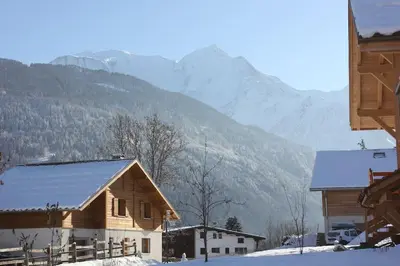 a wooden house with mountains in the background at Chalet des Morets in Saint-Gervais-les-Bains