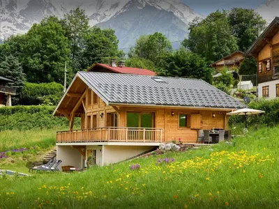 a house in a field with a mountain in the background at Chalet Etoile Nordique - OVO Network in Saint-Gervais-les-Bains