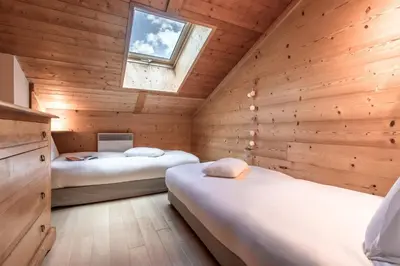 two beds in a wooden room with a window at Grand Balcon 3 - Calme - Vues - Cosy in Les Houches