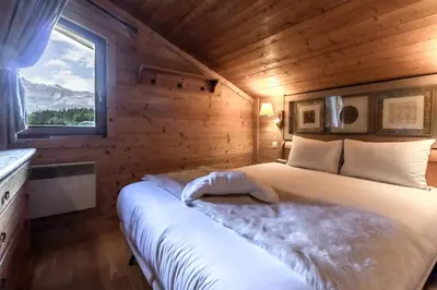 a bed in a wooden room with a window at Grand Balcon 3 - Calme - Vues - Cosy in Les Houches