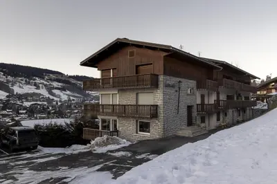 a building on a snow covered hill with at Le Farniente - Central - Chaleureux in Megève