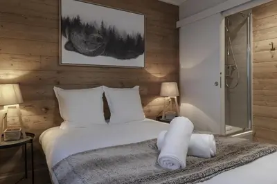 a bedroom with a bed with white sheets at Le Farniente - Central - Chaleureux in Megève