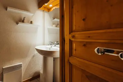 a bathroom with a sink and a wooden door at Appt MIAGE - 2 pièces cabine, terrasse & piscine in Saint-Gervais-les-Bains