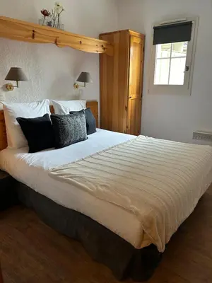 a bedroom with a large bed with white sheets and pillows at Appt MIAGE - 2 pièces cabine, terrasse & piscine in Saint-Gervais-les-Bains