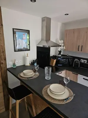 a kitchen with a table with plates and glasses on it at Charmant T1 montagnard proche télécabine in Saint-Gervais-les-Bains