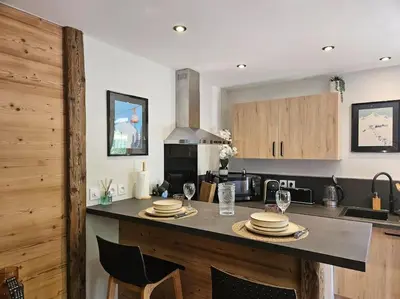 a kitchen with a table with plates and wine glasses at Charmant T1 montagnard proche télécabine in Saint-Gervais-les-Bains