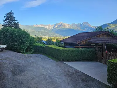 a house with a hedge fence and a pavilion with mountains at Charmant T1 montagnard proche télécabine in Saint-Gervais-les-Bains