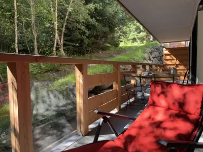 a screened in porch with chairs and a table at Le lodge de l alpage - Ski in ski out - 2 chambres 1 cabine in Combloux
