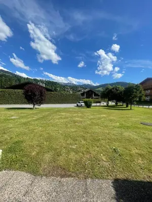 a grassy yard with a house in the background at le jaillet in Megève