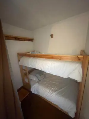 a bedroom with a bunk bed with white sheets at le jaillet in Megève