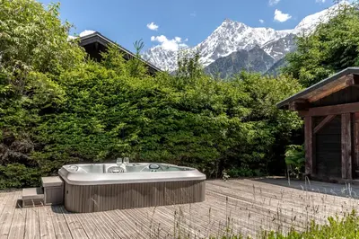 a bath tub sitting on a patio with mountains in the background at Balcon De l Europe - Jacuzzi prive - Vues in Les Houches
