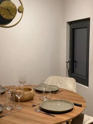 a wooden table with wine glasses and a clock on the wall at Appartement Brévent in Les Houches