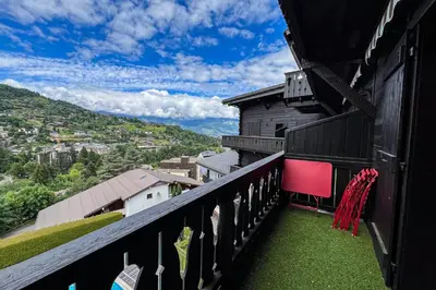 a balcony with green grass and a building at Comfortable studio with pool and view in Saint-Gervais-les-Bains