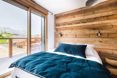 a bedroom with a wooden accent wall and a bed at Appartement Boréal - At the summit of Combloux in Combloux