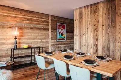 a dining room with a wooden wall with a table and chairs at Appartement Boréal - At the summit of Combloux in Combloux
