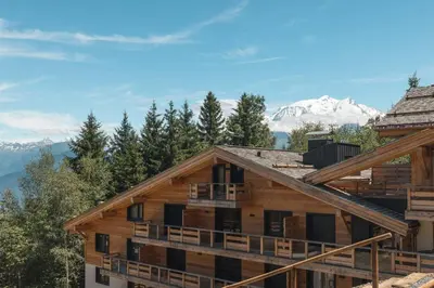 a log cabin with mountains in the background at Appartement Boréal - At the summit of Combloux in Combloux