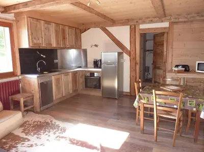 a kitchen with a table and a stainless steel refrigerator at Premier étage d'une ferme rénovée in Passy