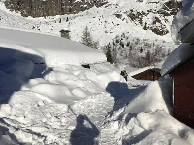 a person standing in the snow next to a house at Premier étage d'une ferme rénovée in Passy