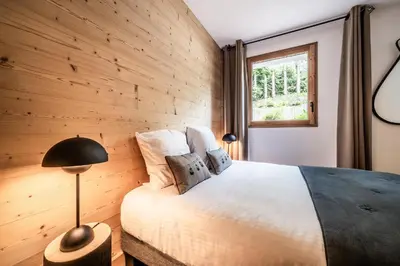 a bedroom with a bed with a wooden wall at Apartment Lupin Megève - by EMERALD STAY in Megève