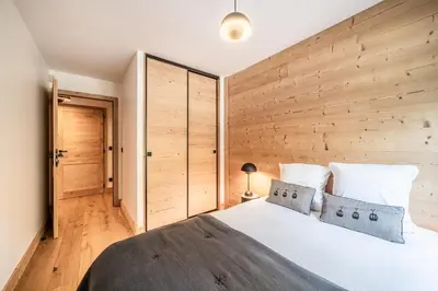 a bedroom with a large bed with a wooden wall at Apartment Lupin Megève - by EMERALD STAY in Megève