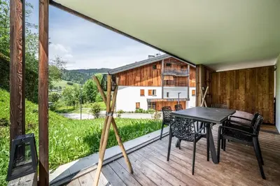a view from the deck of a house with a table and chairs at Apartment Lupin Megève - by EMERALD STAY in Megève