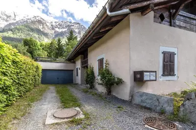 a house with a garage and a mountain at La Poya haut - Calme - Vues magnifiques in Les Houches